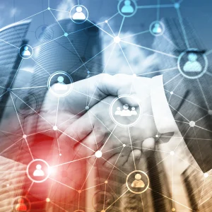 A handshake in front of a financial district backdrop with faded diagrams of people